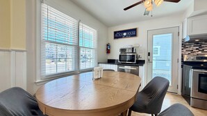A kitchen with a dining table, chairs, a ceiling fan, and a view through large windows. - Charming 3-bedroom townhome 2 blocks from ocean and bay, in town of Stone Harbor (Stone Harbor)