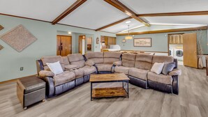 A spacious living area with a sectional sofa, a coffee table, and a wooden ceiling. - 4BR Retreat w/ KING Bed, Hot Tub & Prime Location (Owasso)