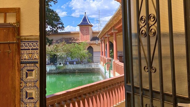 A view through an open gate with a decorative lantern above, leading to a courtyard with a water feature and a building with a tower. - Room-orange Room Your Refuge of Tranqu (Alzira)
