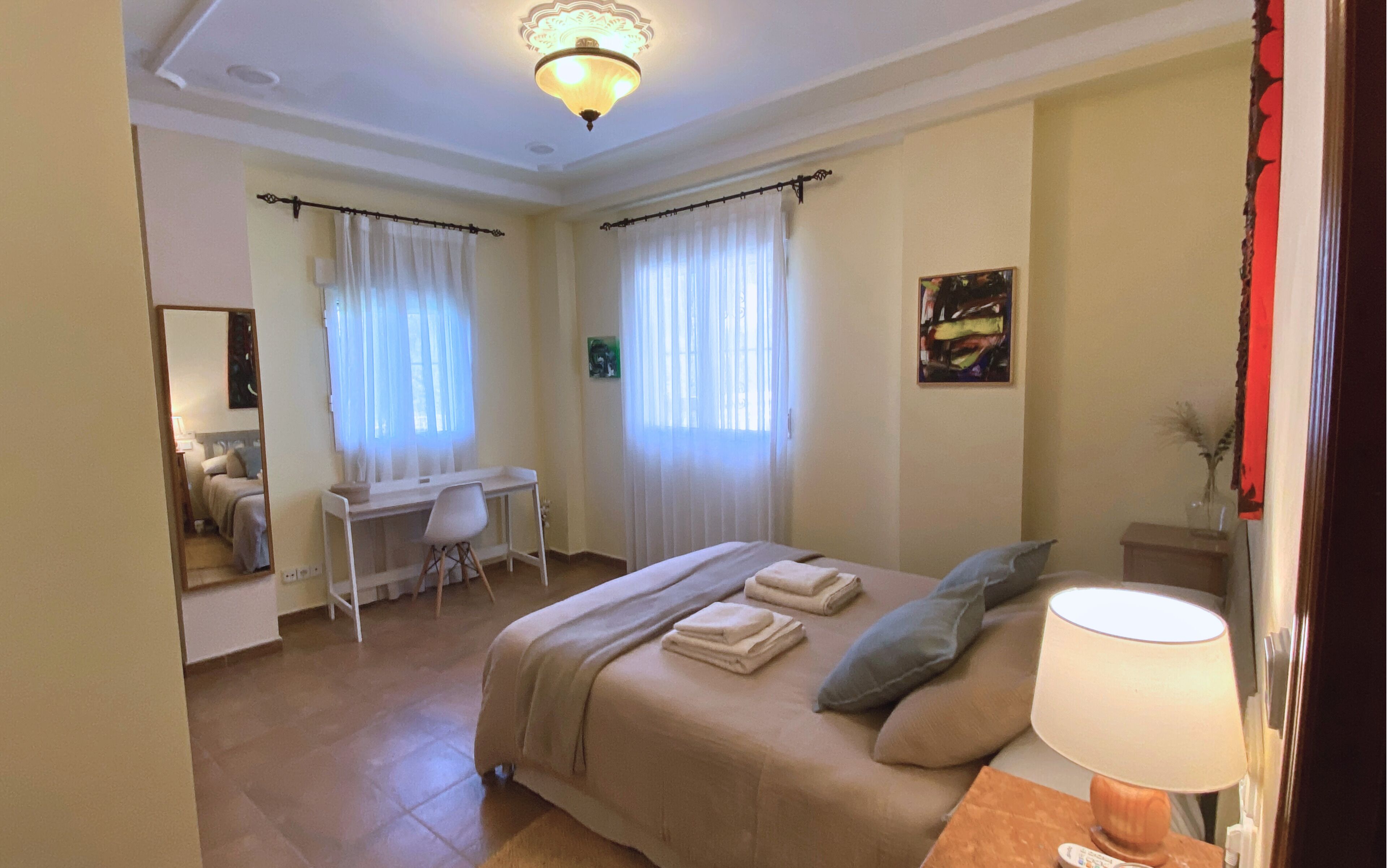 Una habitación de hotel con cama, escritorio, silla y lámpara.