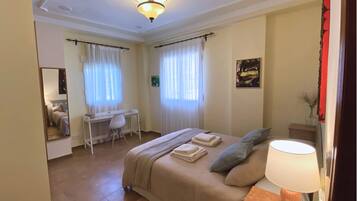 Una habitación de hotel con cama, escritorio, silla y lámpara.