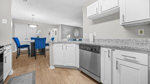 Une cuisine moderne avec des meubles blancs, un lave-vaisselle et un plan de travail en granit.