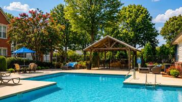 A clear blue swimming pool with lounge chairs and a covered seating area.