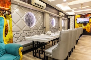 Un restaurante con una larga mesa dispuesta para comer, asientos acolchados y paneles decorativos en la pared.
