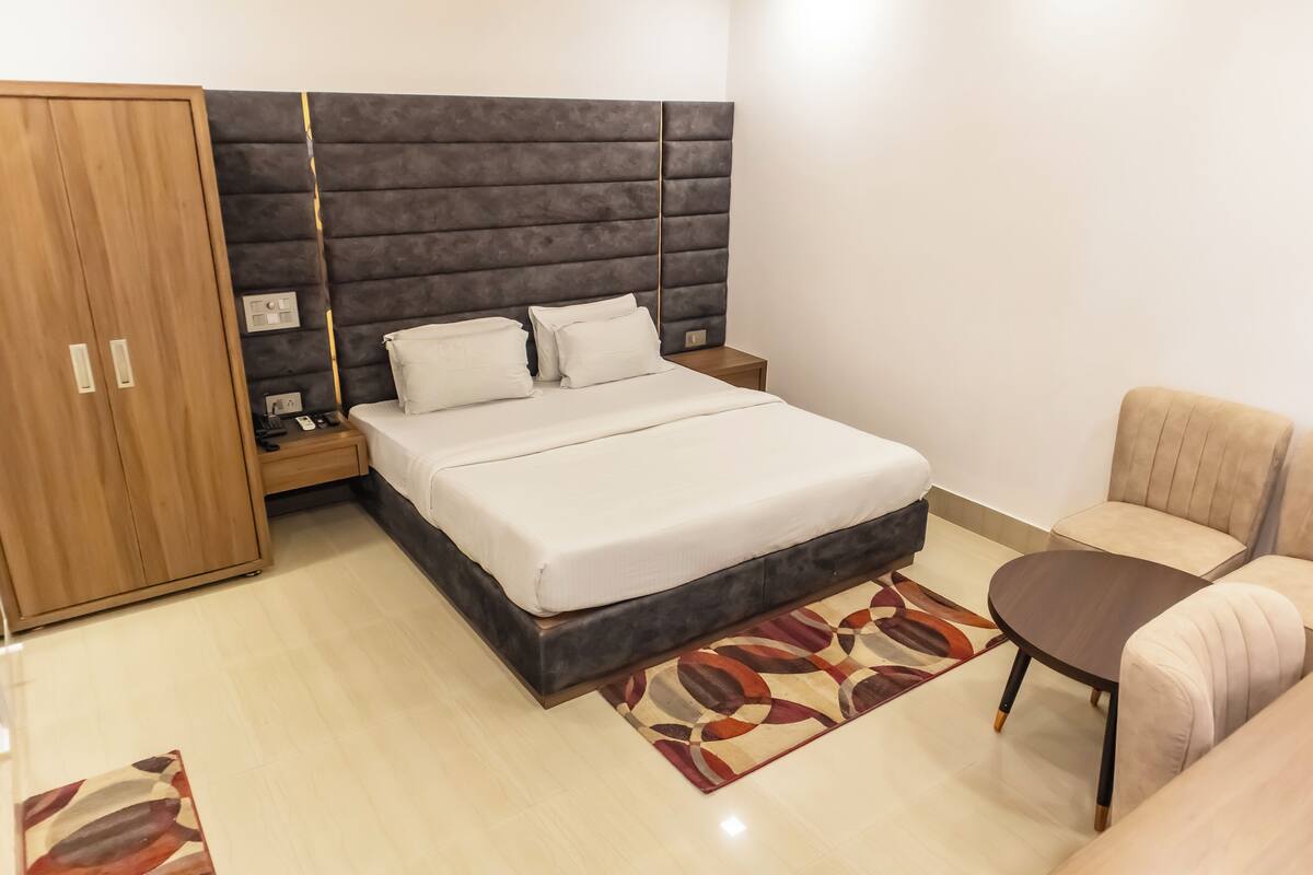 Ein modernes Schlafzimmer mit einem großen Bett, einem Holzschrank, einem kleinen Tisch und einer Couch.
