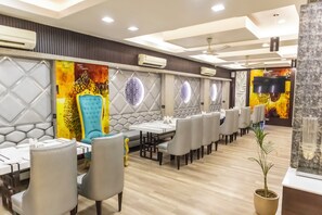 Un restaurante con varias mesas y sillas, unidades de aire acondicionado y una pared decorativa con diseños circulares.