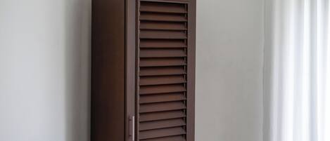 A tall, narrow wardrobe with horizontal slats, a handle, and a flat top.