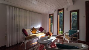 A room with a white sofa, a white armchair, a small table, and a red patterned rug. - Greenwood Edge Kandy (Kandy)
