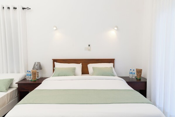 Habitación de hotel con una cama grande, dos mesitas de noche, una lámpara y un termostato instalado en la pared.