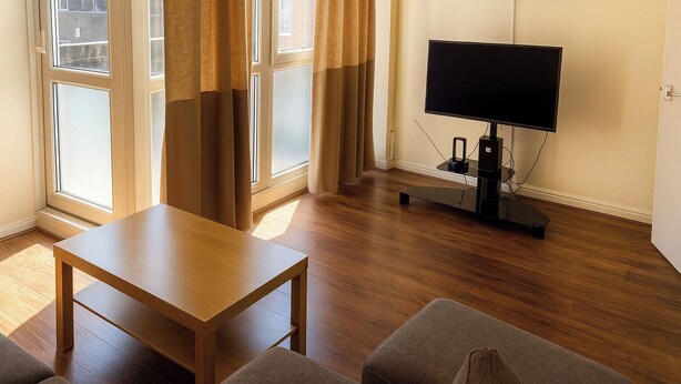 A room with a wooden table, a flat-screen TV, and a couch. - 3br-sleeps5-balcony-centrallondon-ws95 (London)