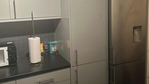 A kitchen with white cabinets, a stainless steel refrigerator, and a microwave on the counter. - 3br-sleeps5-balcony-centrallondon-ws95 (London)
