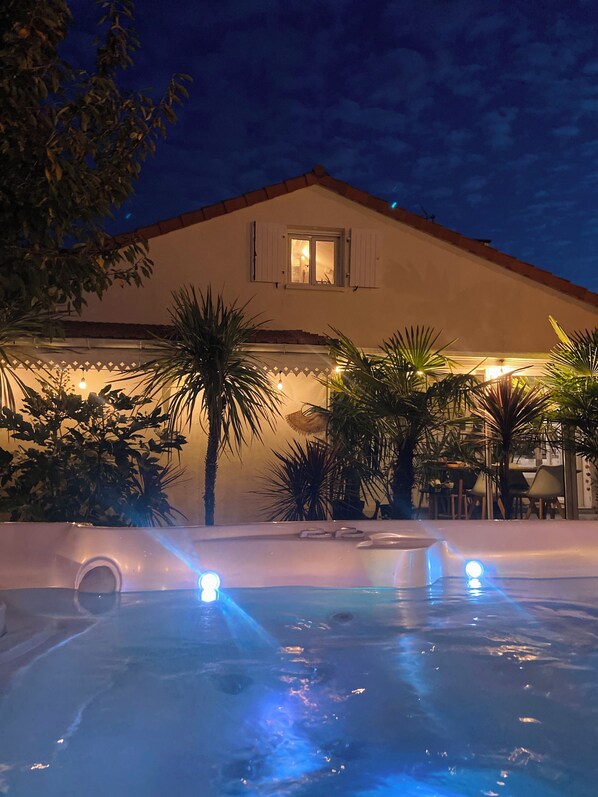 Un edificio con zona de piscina, que incluye un jacuzzi y una fuente de agua con luces.