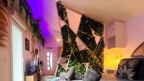 Een moderne slaapkamer met een bed, een houten vloer, een wandplantaankast en een televisie op een houten voetstuk.