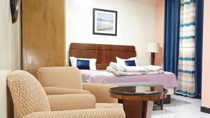 A hotel room with a bed, a sofa, a small table, and a painting on the wall. - AMSY HOTEL AMSY HOTEL (Dakar)