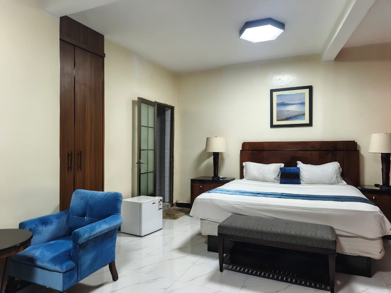 Une chambre d’hôtel comprenant un lit, des tables de chevet, une chaise, un bureau et une armoire.