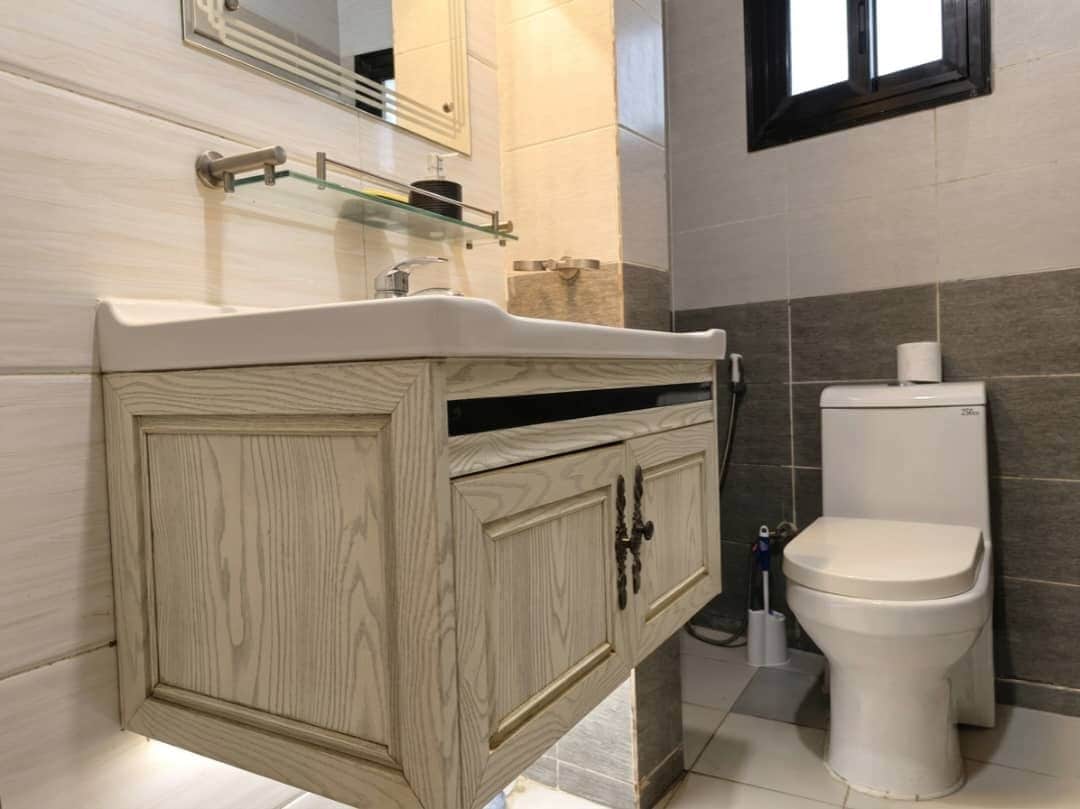 Une salle de bain avec un meuble-lavabo en bois, des toilettes et un miroir.