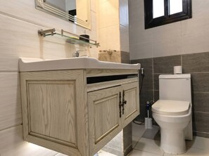 A bathroom with a wooden vanity, a toilet, and a mirror. - AMSY HOTEL AMSY HOTEL (Dakar)