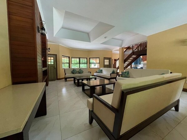 A spacious living area with a sofa set, a coffee table, and a dining table.
