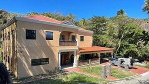 A two-story house with a red roof, a balcony, and a covered porch.