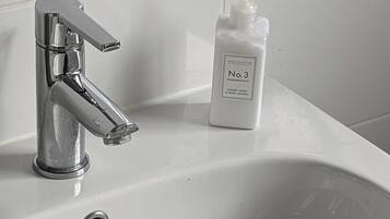 A bathroom sink with a chrome faucet and a bottle of Hotel Collection No. 3 Pomegranate Luxury Hand & Body Lotion.