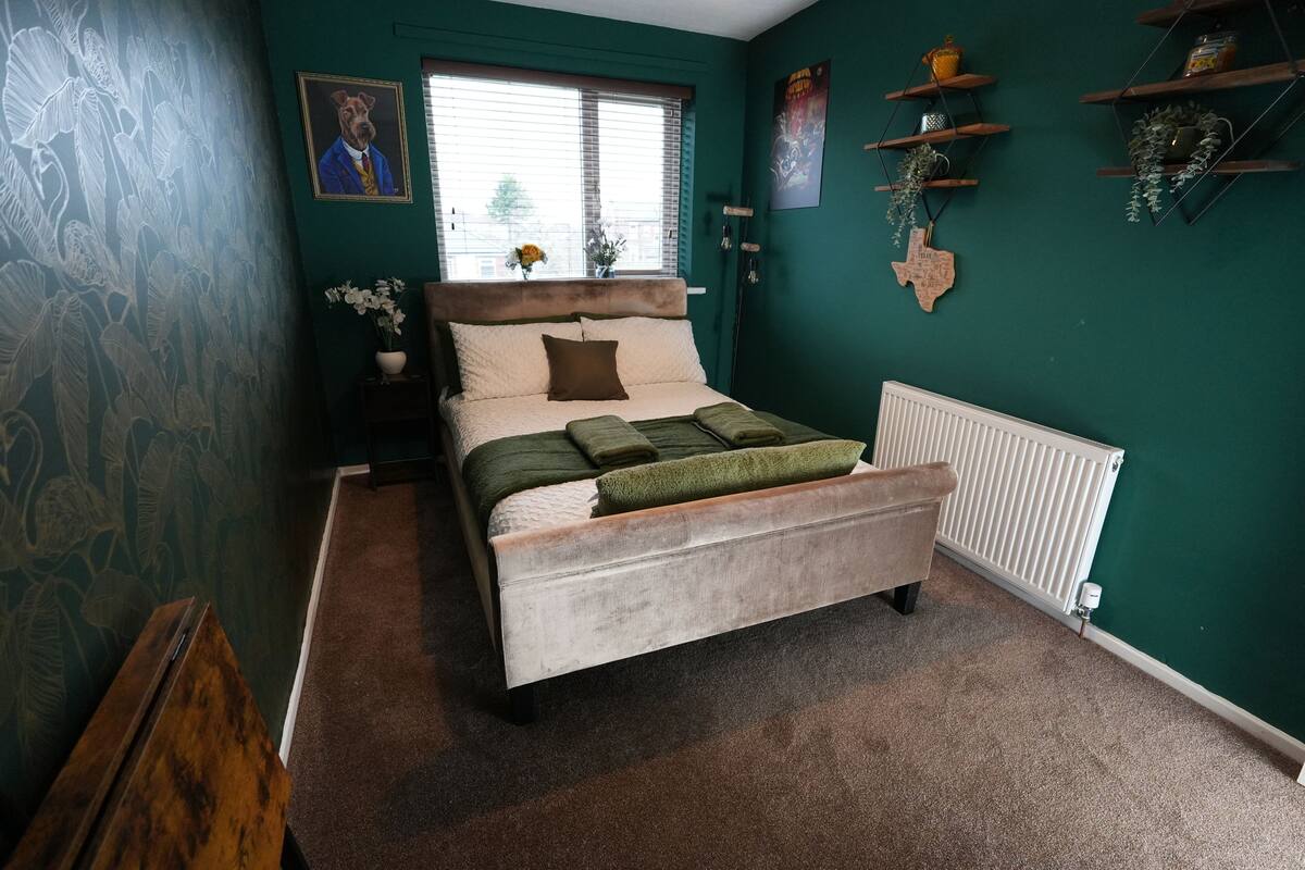A bedroom with a bed, a window, a radiator, and wall decorations.
