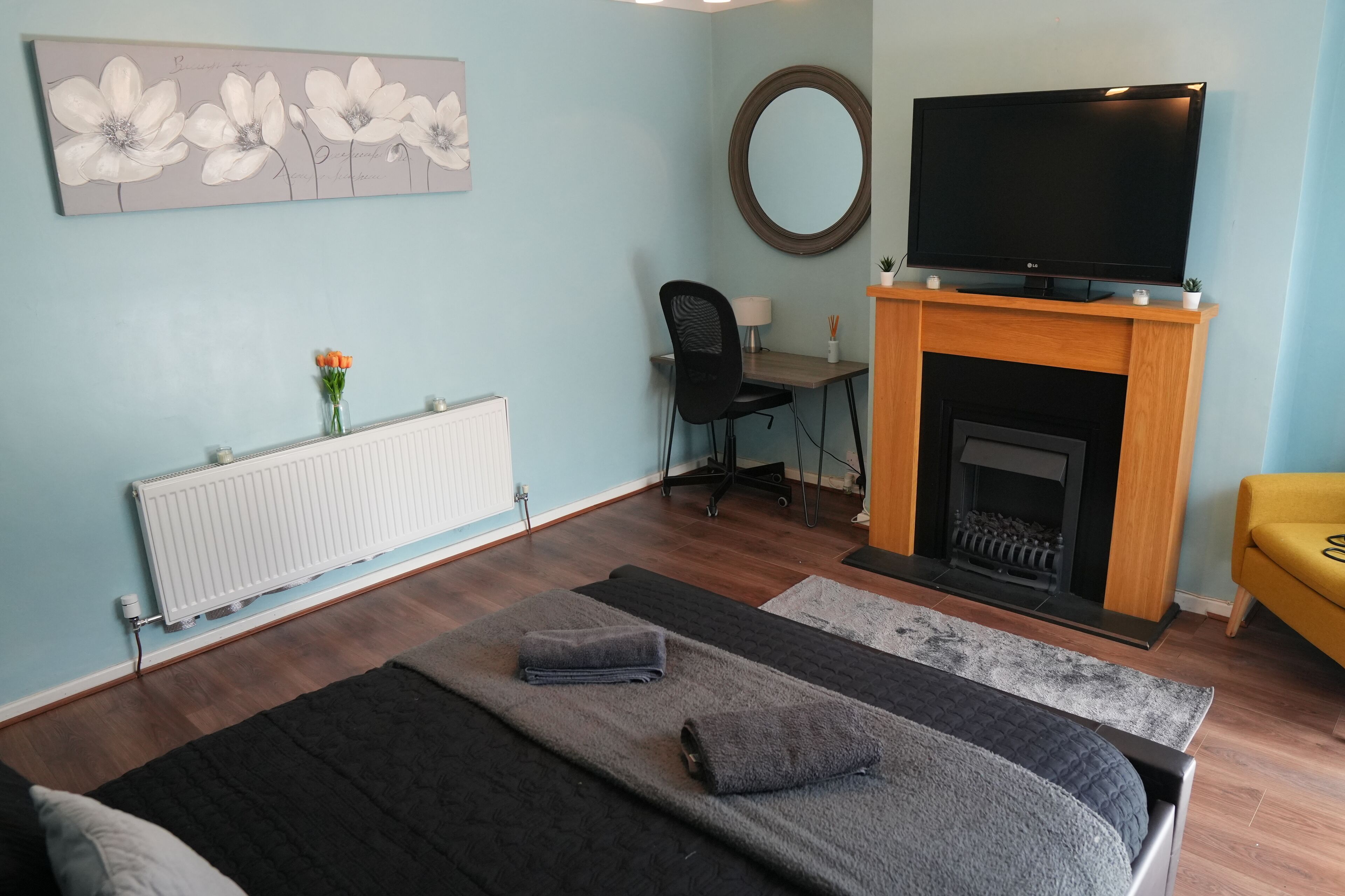 Un dormitorio con cama, televisor, chimenea, escritorio y silla.