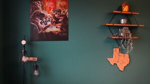 Paredes com um quadro de cães, uma decoração em formato do Texas e uma estante com objetos decorativos.