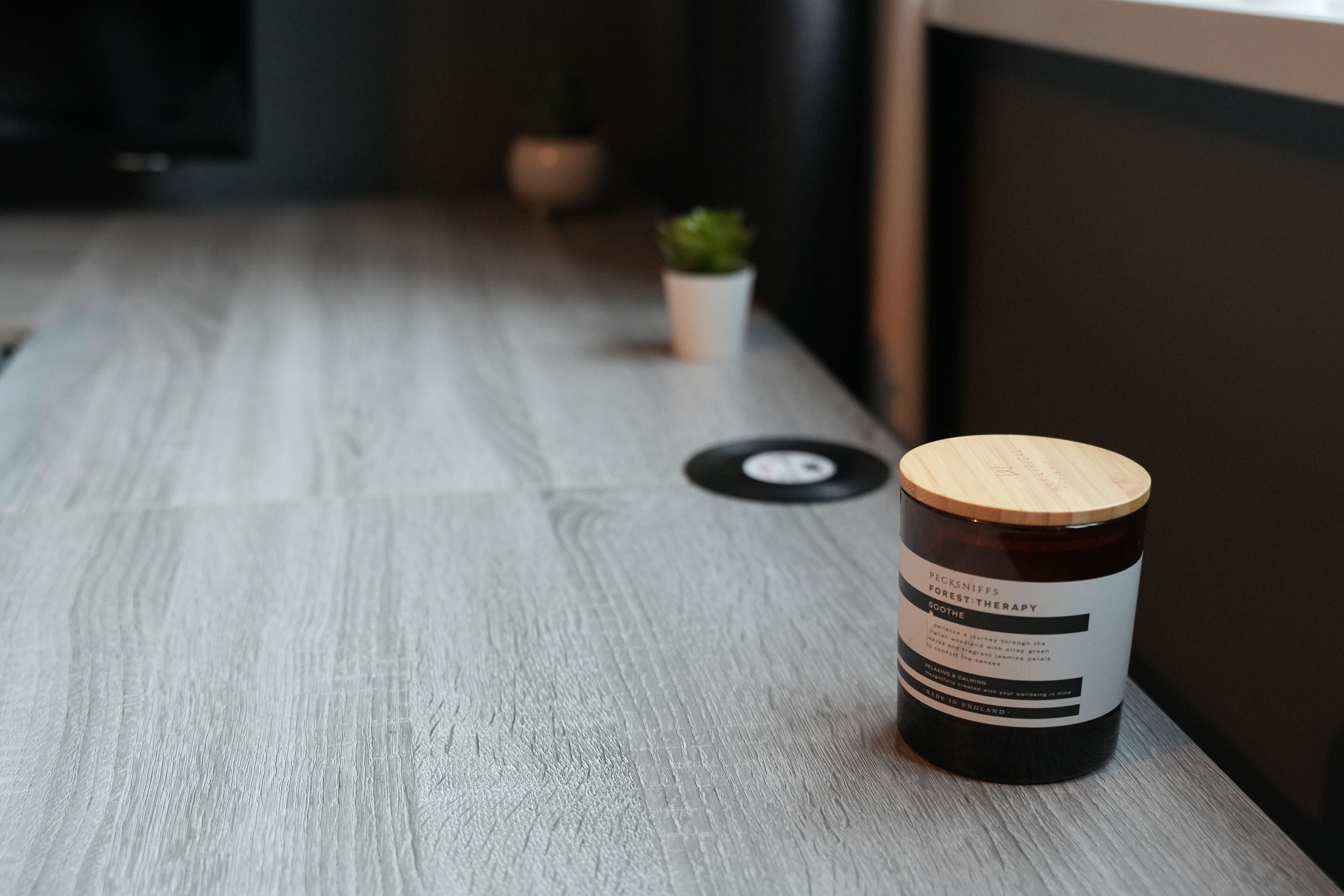 Une table en bois sur laquelle se trouve un pot de produit de bain de pieds « Pecksniffs Forest Therapy ».