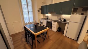 A compact kitchen with a dining table, a washing machine, an oven, and a refrigerator.