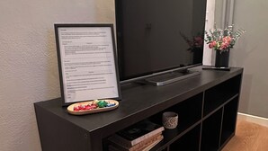 A black entertainment center with a flat-screen TV, a framed menu, and a small plant.