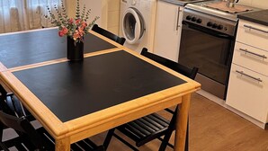 A compact kitchen with a washing machine, oven, and a dining table with chairs.