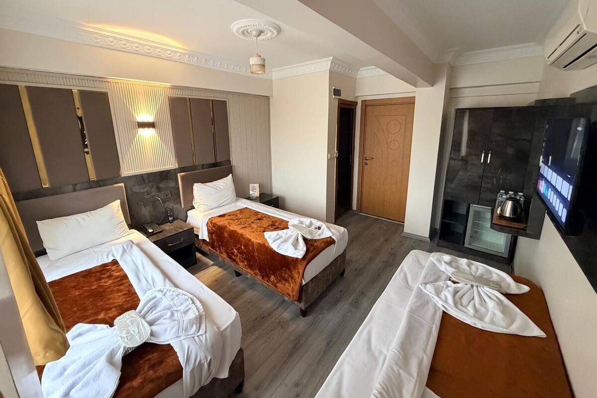 A hotel room with two beds, a TV, a minibar, and a shower area.