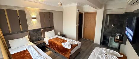 Habitación de hotel con dos camas, televisión, minibar y zona de ducha.