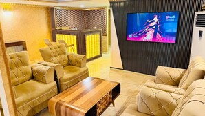 A modern living room with leather sofas, a wooden coffee table, a TV, and a patterned wall. - Alklas Hotel (Istanbul)