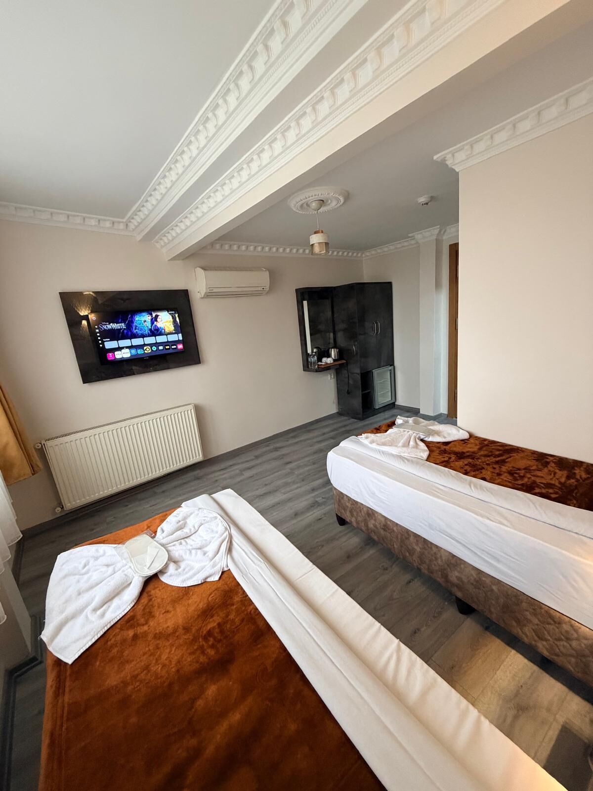 Een hotelkamer met twee bedden, een televisie, een airconditioning en een kledingkast.
