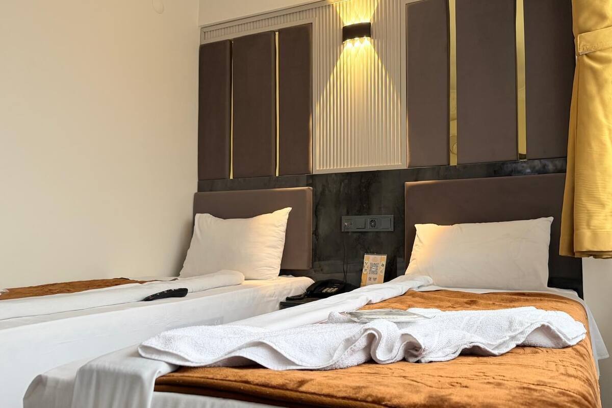 A hotel room with two beds, a marble headboard, and a bedside table with a lamp.
