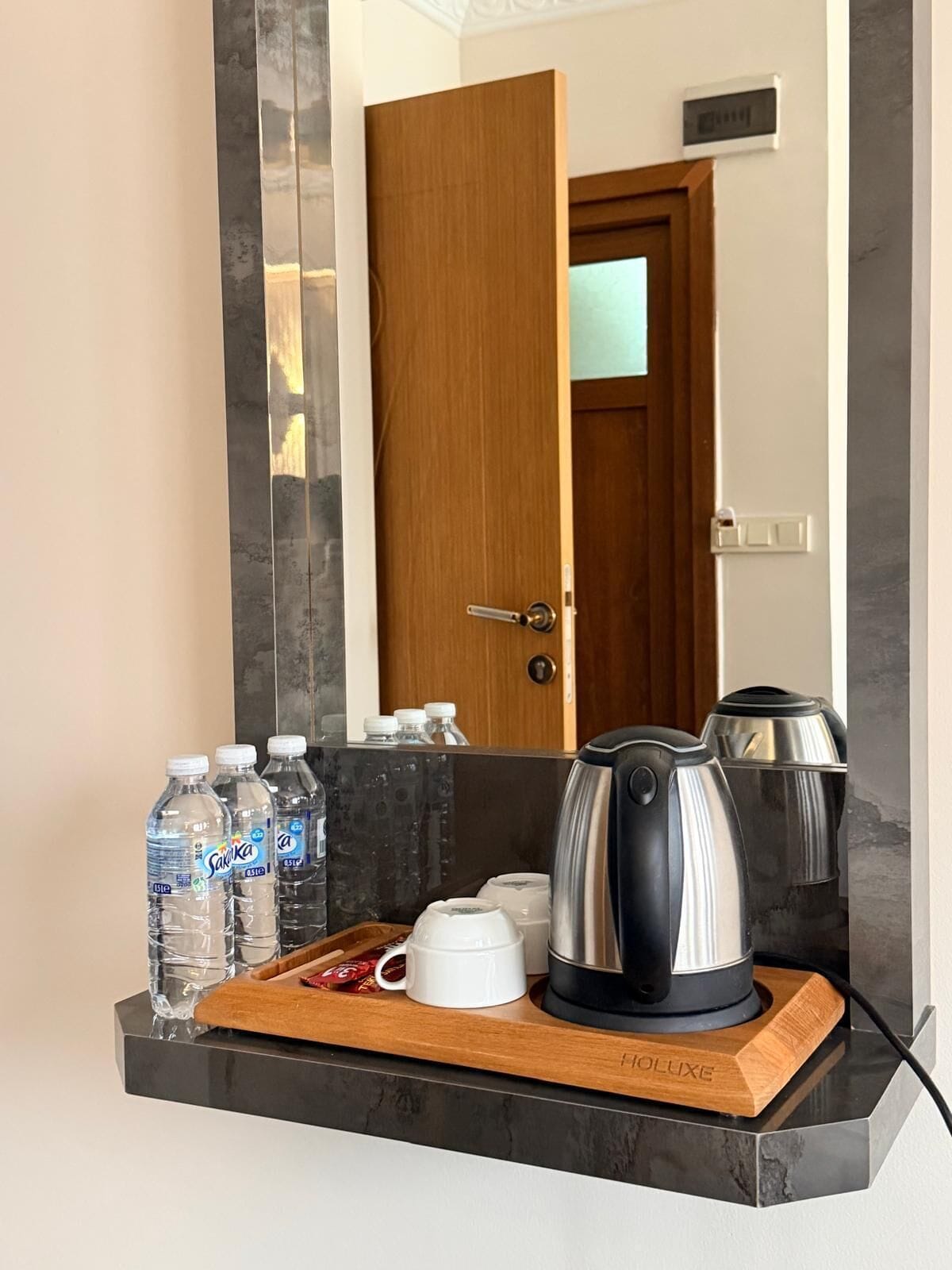 Ein Badezimmer mit Marmortisch, einer Kaffeemaschine, einem Wasserkocher und abgefülltem Wasser.