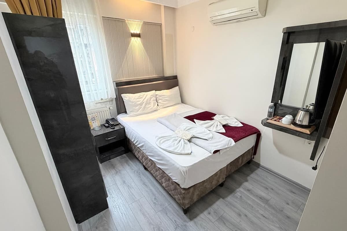 A hotel room with a bed, bedside table, and a mirror.