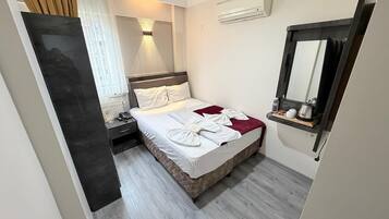 A hotel room with a bed, bedside table, and a mirror.