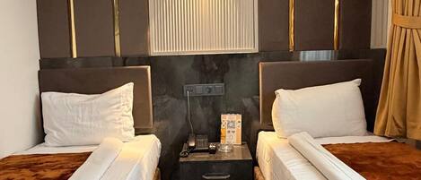 A hotel room with two beds, a nightstand, a wall-mounted lamp, and a mirror.