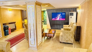 A spacious living room with a television, comfortable seating, a decorative column, and a fireplace. - Alklas Hotel (Istanbul)