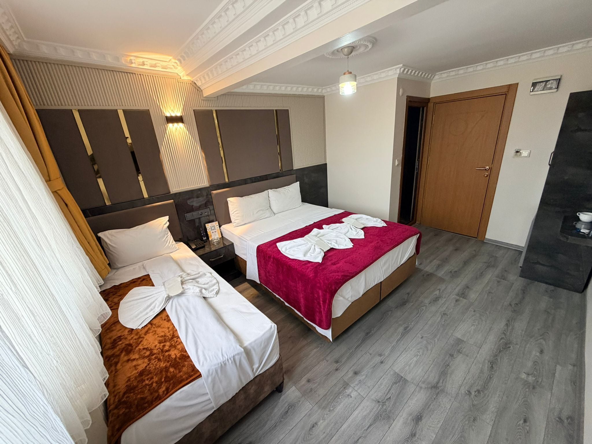 Quarto de hotel com duas camas, porta de madeira e lareira embutida.