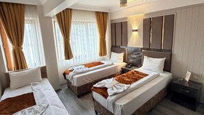 A hotel room with three beds, a large window with curtains, a bedside table, and a nightstand. - Alklas Hotel (Istanbul)