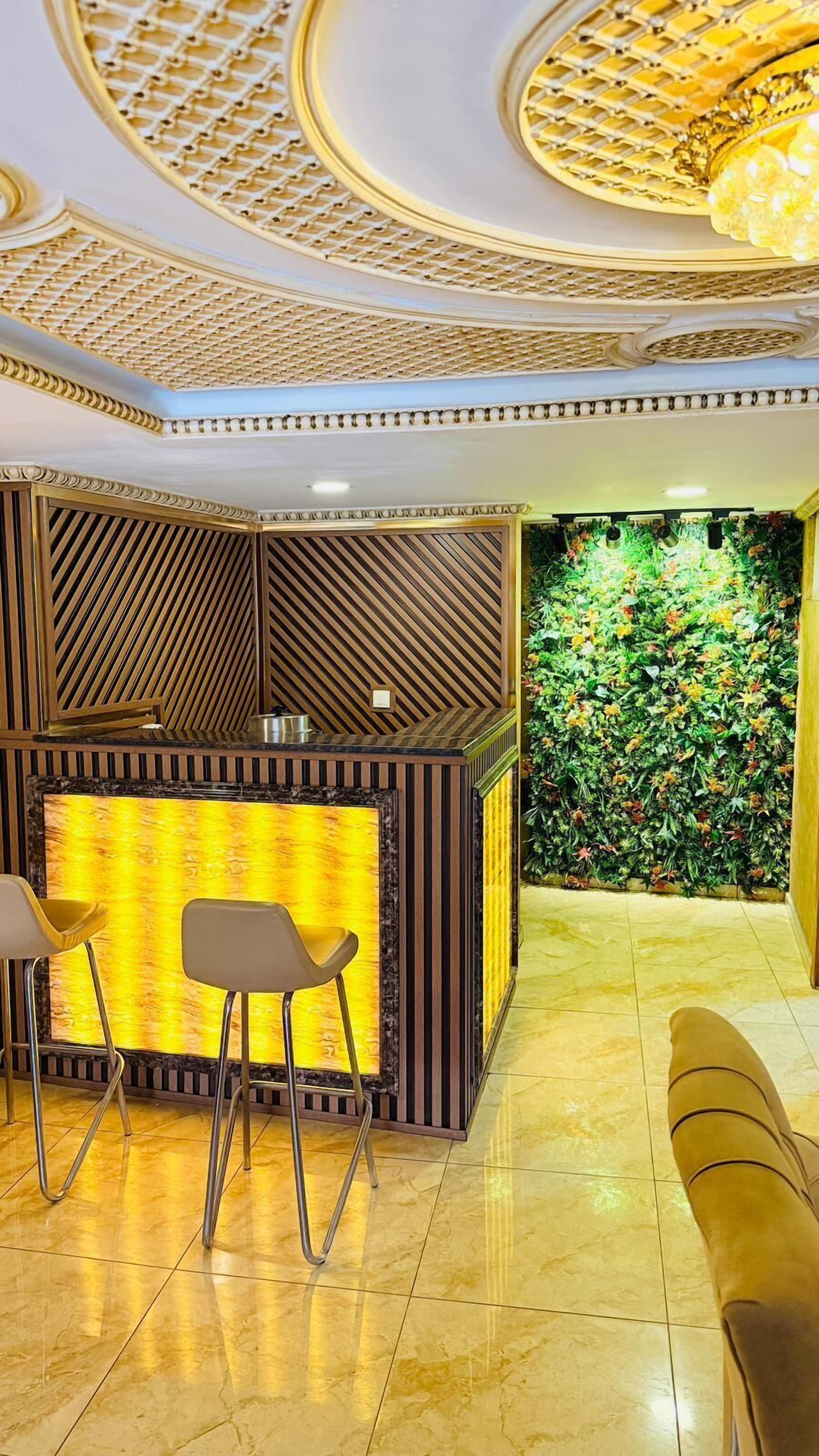 A reception area with a patterned wall, a reception desk, two bar stools, and a seating area with a sofa.