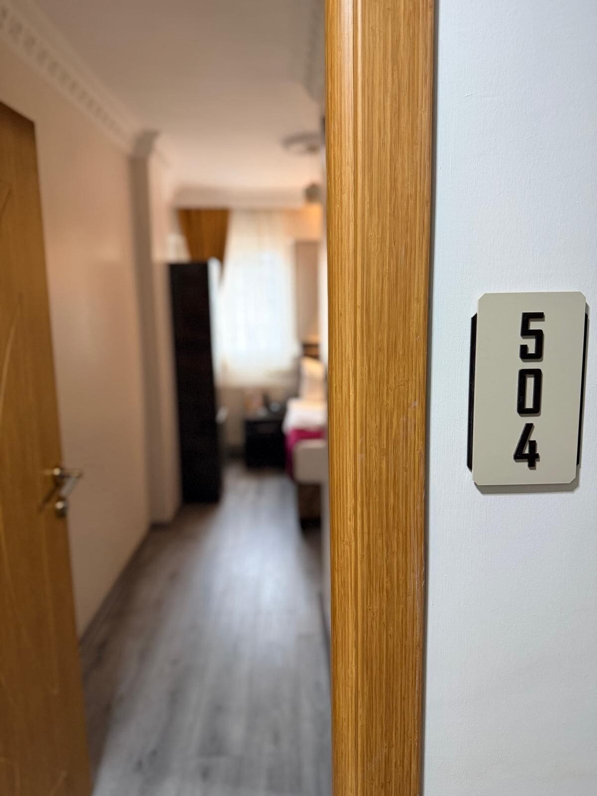 A hallway with a door leading to a room, a number plate with '504' on it, and a blurred background suggesting a residential setting.