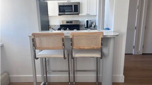 A compact kitchen with two bar stools, a microwave, and a coffee maker. - Charming 2-bedroom Tribeca apartment with views (New York)