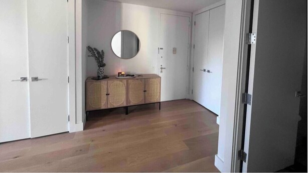 A hallway with white doors, a round mirror, a wooden cabinet, and a small plant. - Charming 2-bedroom Tribeca apartment with views (New York)