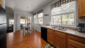 A modern kitchen with wooden cabinets, a dishwasher, and a dining area with a table and chairs.