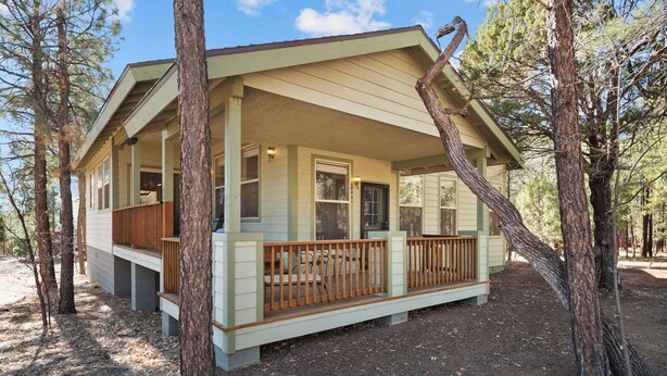 A cabin with a porch, surrounded by trees.