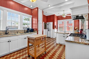 Una cocina con armarios blancos, una mesa de madera y un suelo con patrón de espiga.